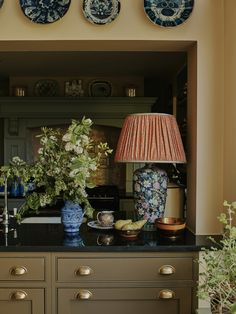 a table with vases and flowers on it in front of a cabinet filled with plates