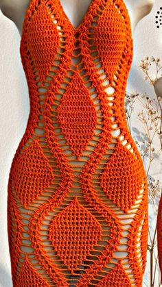 an orange crocheted dress is displayed on a mannequin