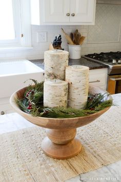 diy birch candle holders in a wooden bowl with greenery and pine cones on top