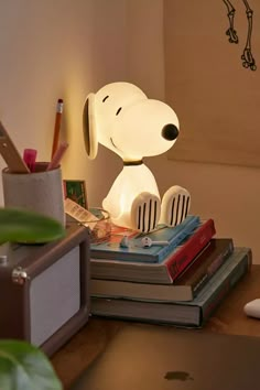 a lamp that looks like a dog sitting on top of books next to a laptop