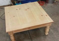 a wooden table sitting on top of a floor next to a pile of tools and other items