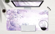 a computer mouse and keyboard sitting on top of a purple flowered desk mat with glasses