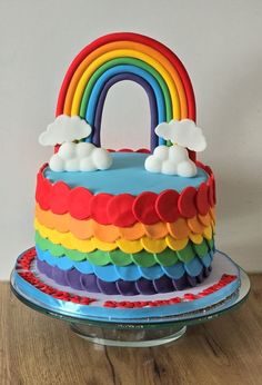 a rainbow cake with clouds and a rainbow on top