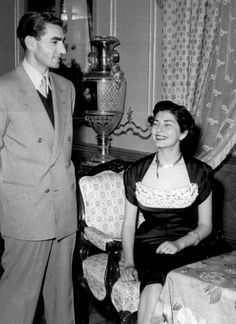 an old black and white photo of a man standing next to a woman