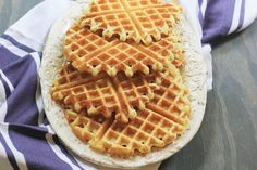 a waffle sitting on top of a white plate next to a purple and white towel