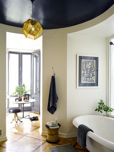 a bath room with a tub and a table next to a window on the wall