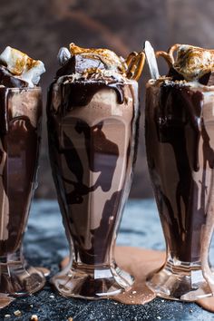 three chocolate milkshakes are sitting on a table