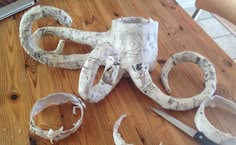 an octopus made out of paper sitting on top of a wooden table next to scissors