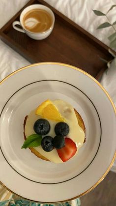 a plate topped with fruit and cream on top of a table next to a cup of coffee