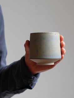 a person holding a gray cup in their hand and wearing a blue shirt on the other side