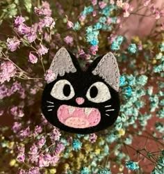 a close up of a cat brooch with flowers in the background