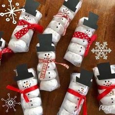 snowmen made out of toilet paper wrapped in red and white ribbon on a wooden table