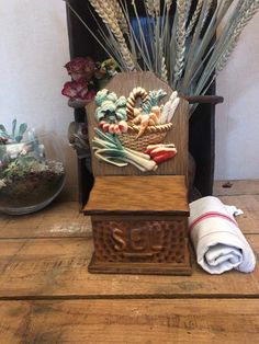 an old wooden chair with dried flowers and other items in it sitting on a table