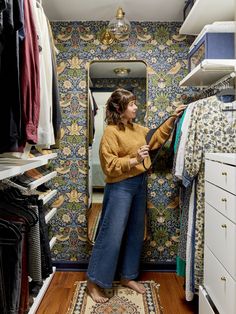 a woman is looking at her clothes in the closet