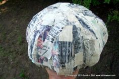 a person wearing a paper mache hat with newspaper clippings on it's side