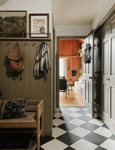 a hallway with checkered flooring and coat racks on the wall next to an entry door