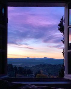 an open window with the view of mountains in the distance at sunset or sunrise time