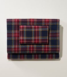 a plaid sheet set on top of a white wall next to a red and blue pillow