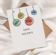 a greeting card with three ornaments hanging from it's sides on top of a bed