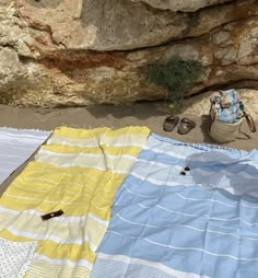 there are towels and sandals on the ground next to some rocks with a bag in it