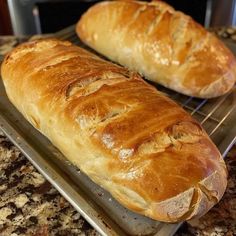 two loaves of bread sitting on top of a metal rack next to each other