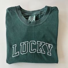 Celebrate St. Patricks Day with the varsity print LUCKY tee!  Please wash on gentle cycle and dry on low.  If you are wanting a different design, wording, or a different clothing style, please send me a message so we can discuss the details. Sporty T-shirt With Embroidered Graphics For Game Day, Casual College Tops With Graphic Embroidery, Casual College Tops With Embroidered Graphics, Casual Tops With Embroidered Graphics For College, Graphic Tee With Embroidered Graphics For College, Varsity Tops With Letter Embroidery For Streetwear, Varsity Crew Neck T-shirt With Screen Print, Collegiate Tops With Embroidered Graphics For College, Varsity Cotton T-shirt With Text Print