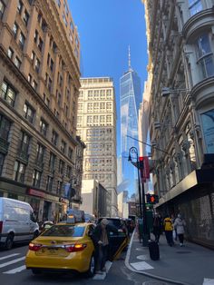 a yellow car is stopped at an intersection in the city with tall buildings behind it