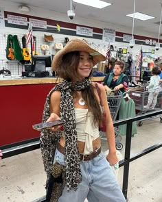 a woman with a hat and scarf standing in front of a shopping cart holding a cell phone