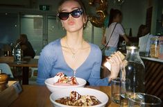 a woman sitting at a table in front of a plate of food with ice cream on it