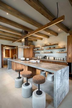 a kitchen with an island and stools next to it in the middle of the room