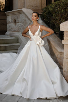 a woman in a white wedding dress standing on steps with her hands on her hips