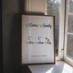 a white framed sign sitting on top of a window sill next to a window