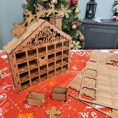 a christmas tree is in the background next to a wooden house and other pieces of wood