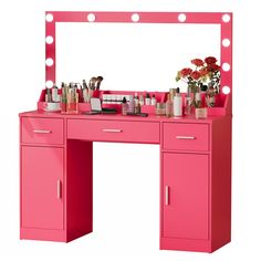 a pink vanity with lights and flowers on it