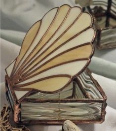 two decorative seashells sitting on top of a white cloth covered tablecloth next to each other