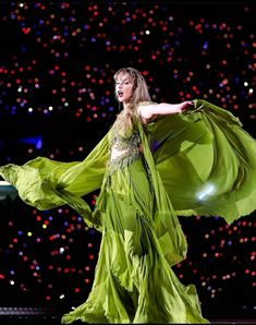 a woman in a green dress is performing on stage