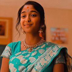 a woman in a blue sari is smiling for the camera