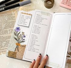 an open book sitting on top of a table next to some pens and paper items