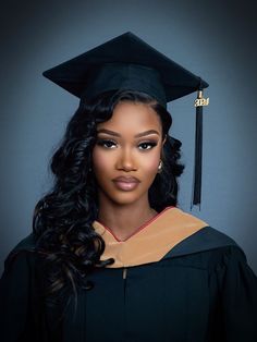 a woman wearing a graduation cap and gown posing for a photo in front of a gray background