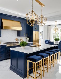 a kitchen with blue cabinets, gold accents and an island in the middle that has four stools