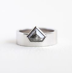 a diamond shaped ring sitting on top of a white surface with a black diamond in the center