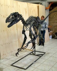 a woman standing next to a dinosaur skeleton