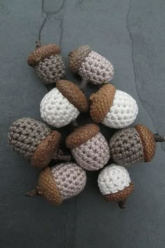 several knitted acorns are arranged in a circle on the ground, one is brown and white