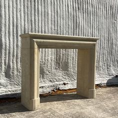 an empty stone bench sitting in front of a white wall with snow on the ground