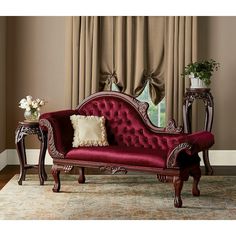 a red couch sitting on top of a wooden floor next to a table with flowers