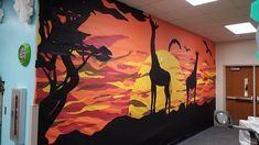 an office decorated with giraffes and trees on the wall in front of it