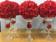 three clear vases with red flowers in them