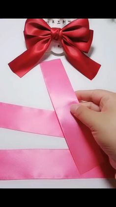 someone is cutting ribbon with scissors on top of the paper and another piece of pink tape