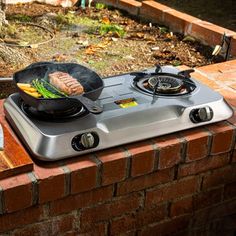 a stove top with some food cooking on it's burners in front of a brick wall