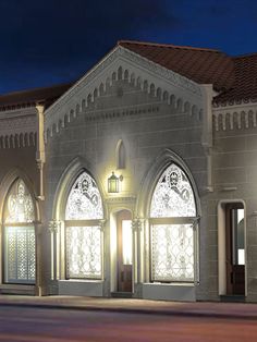 an old church lit up at night with lights on the front and side windows,